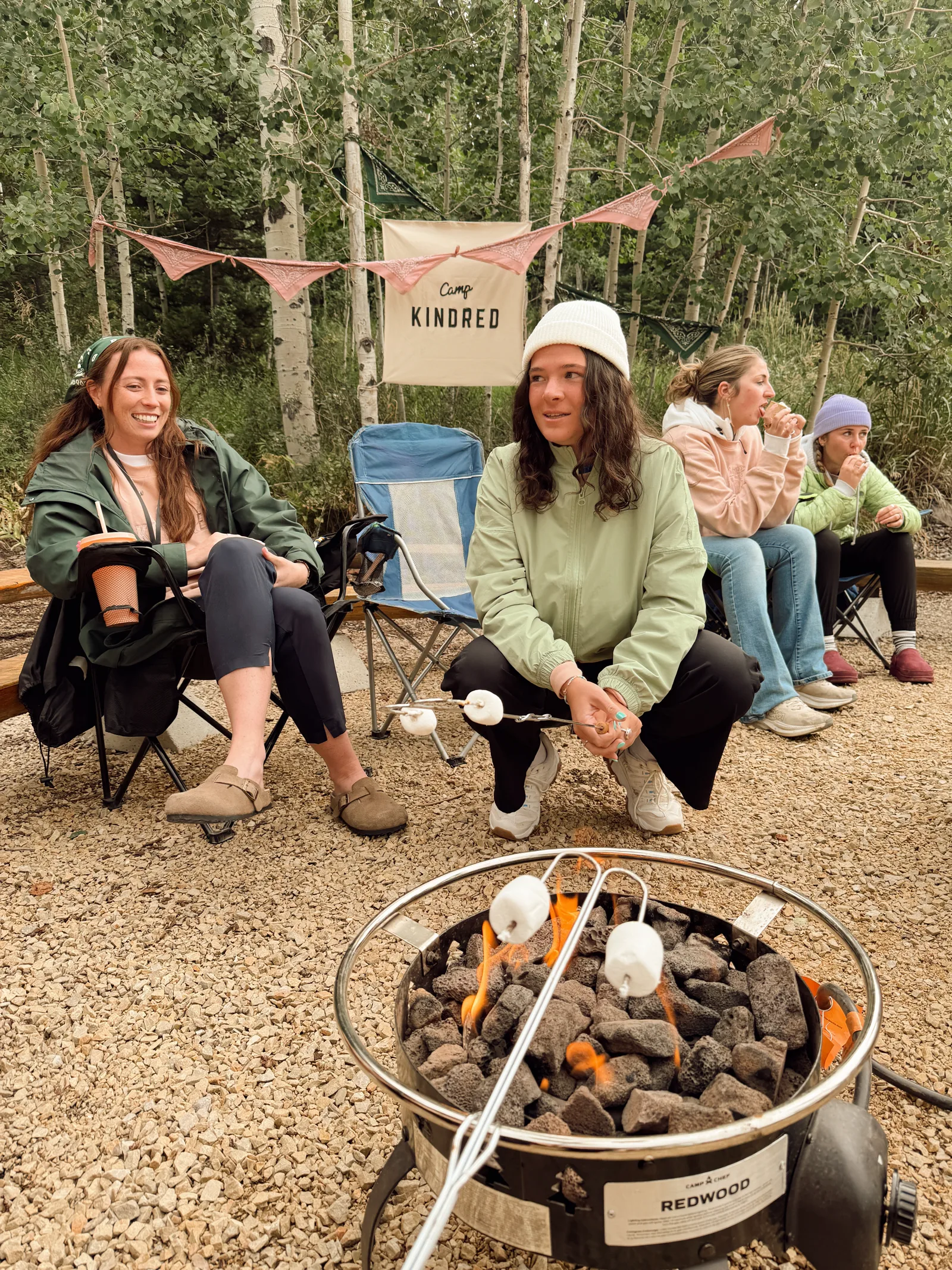 Camp Kindred friends gathered around a fire in the aspen grove